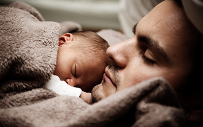 A father and his infant child asleep together.