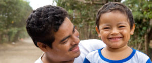 A father looks at his smiling son.