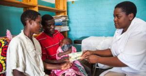 Couple and child with health professional in Rwanda. Photo by Perttu Saralampi for Equimundo.